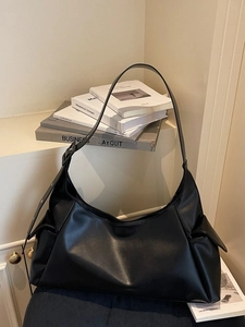 Minimalist black leather tote bag with wide adjustable strap and side pockets for women