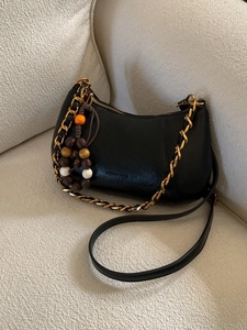 Sac bandoulière demi-lune en cuir noir avec chaîne tressée et breloque artisanale
