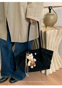 Detail of black suede tote bag with cute bear pendant in a vintage lifestyle setting