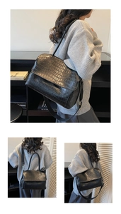 Detailed view of black crocodile pattern leather flap bag with adjustable shoulder strap