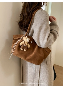 Detail of brown suede tote bag featuring a cute teddy bear charm on a slim shoulder strap