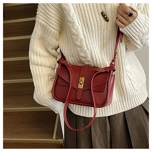 Détail du sac bandoulière en cuir bordeaux avec un fermoir rectangulaire en métal doré