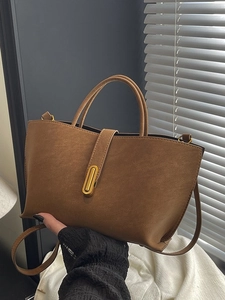 Brown large capacity tote bag with gold buckle and adjustable strap shown by model