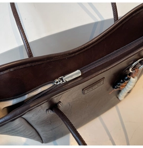 Détail du sac cabas marron foncé avec fermeture éclair argentée et pendentif perlé