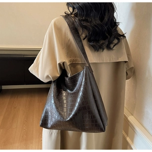 Detail view of deep brown crocodile pattern tote bag with wide shoulder strap