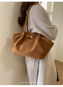 Close-up of a brown suede tote bag with minimalist retro style on a gray wool coat