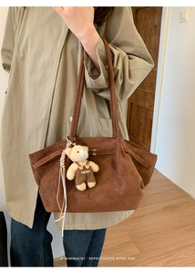 Brown faux suede tote bag with a cute teddy bear charm shown in a cozy indoor setting