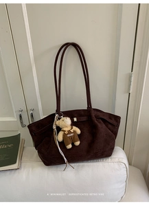 Detail of vintage coffee brown suede tote bag featuring a teddy bear charm and magnetic buckle