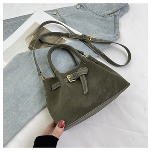 Detail of olive green suede bucket bag with contrast stitching and buckle accent