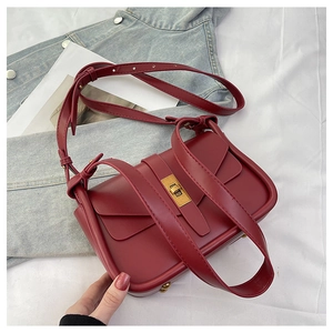 Détail macro du sac bandoulière en cuir mat bordeaux avec boucle rotative en métal doré