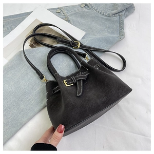 Detail of black matte bucket bag with white contrast stitching and gold hardware