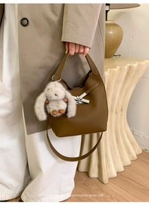 Detail of dark brown leather bucket bag with silver twist lock and bunny charm accessory
