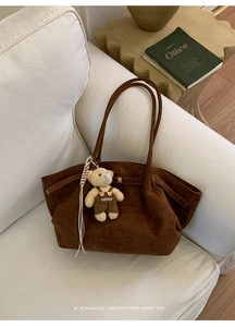 Detail view of large dark brown suede tote bag with cute plush teddy bear charm accessory