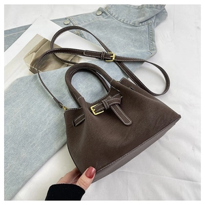 Detail of dark brown suede tote bag with metal buckle strap and dual handles