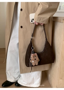 Detail of dark brown suede tote bag with teddy bear pendant and minimalist retro design