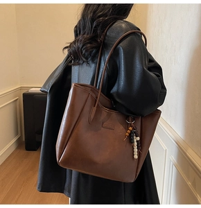 Détail du grand sac cabas marron avec pendentif en perles et texture cuir mate