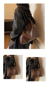 Detail view of large dark brown crocodile embossed leather tote bag on shoulder