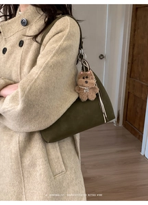 Green shoulder bag with a cute bear pendant worn with a beige vintage coat