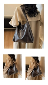 Detail view of deep brown crocodile embossed leather tote bag with shoulder strap