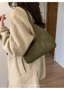 Retro minimalist olive green underarm bag worn over shoulder with contrast stitching