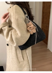 Detail of minimalist black crescent underarm bag with a brown teddy bear charm accessory