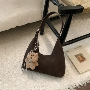 Minimalist coffee brown suede shoulder bag with a cute bear charm on a stylish chair