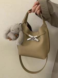 Chic beige lychee leather bucket bag with silver cross lock and plush rabbit charm