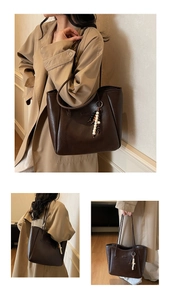 Close-up of a vintage dark brown leather tote bag with a minimalist beaded charm detail