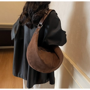 Close-up of brown suede hobo bag with wide shoulder strap and silver buckle detail