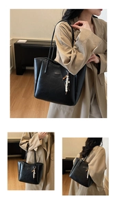 Detail of black leather tote bag featuring a silver fashion tag and beaded tassel accessory