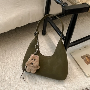 Detail of dark green suede hobo bag featuring a cute brown plush bear charm and soft texture