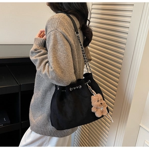Quilted black bucket bag with chain strap and teddy charm shown in a cozy lifestyle setting
