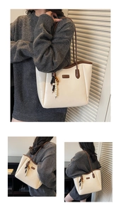 Detail view of cream leather tote bag with brown handles and stylish ethnic beaded pendant
