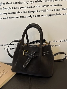 Deep brown bucket bag with white contrast stitching and round handles for crossbody use