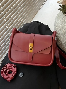 Sac bandoulière en cuir bordeaux classique avec boucle dorée sur fond sombre