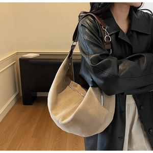 Detail of beige suede tote bag with brown leather shoulder strap and metal ring connectors