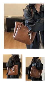 Detailed view of deep brown faux leather tote bag with fashion tag and beaded pendant