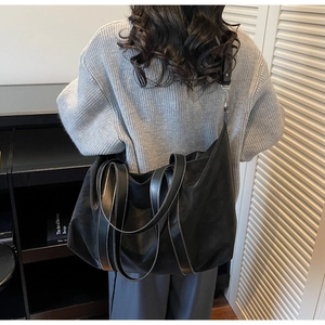 Detail of black nylon tote bag featuring contrast stitching and faux leather handles