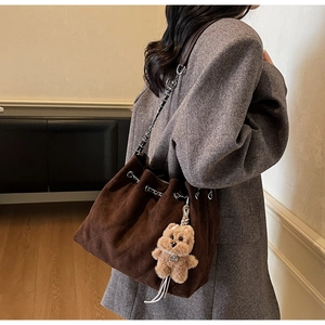Brown suede bucket bag featuring diamond quilted stitching and a cute bear keychain accessory