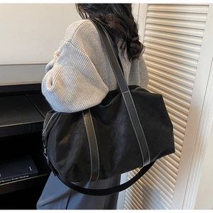 Detail of black tote bag featuring white contrast stitching and dual handle straps