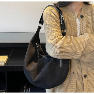 Dettaglio della borsa hobo in camoscio nero con zip argento e tracolla larga regolabile