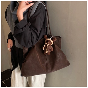 Detail of dark brown faux suede tote bag with a small bear pendant and thin straps