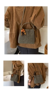 Détail du sac seau en daim vert olive avec pompon en perles et bandoulière réglable