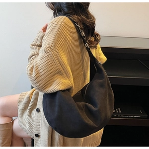 Dettaglio borsa hobo in camoscio nero opaco con cerniera argento su maglione beige