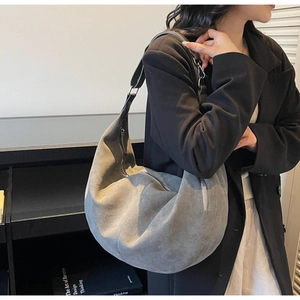 Detail view of large grey suede hobo bag with metal zipper on minimalist shoulder strap