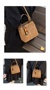 Gros plan du sac seau en daim marron avec gland en perles de bois vintage et bandoulière