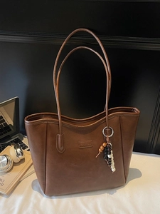 Grand sac cabas vintage marron foncé avec pendentif perlé et ordinateur sur table