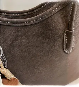 Close-up of vintage brown suede tote bag with contrast stitching and decorative tassel