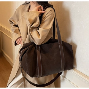 Detailed view of dark brown tote bag featuring white contrast stitching and dual handles