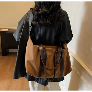 Detail of caramel brown large tote bag with dark brown straps worn by a model